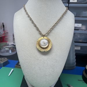 Vintage Hampden-hangerhorloge uit de jaren 70 – 17 juwelen, mechanisch, goudkleurige kast met textuur, 22 inch ketting, werkend