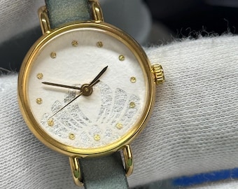 Reloj japonés vintage para mujer: esfera Washi, caja dorada, correa de cuero verde.