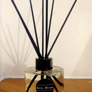 May include: A clear glass diffuser bottle with black reeds and a black label that says "Bath Bliss".
