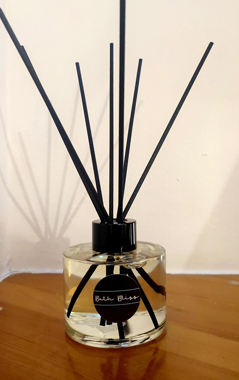 May include: A clear glass diffuser bottle with black reeds and a black label that says "Bath Bliss".