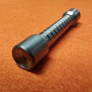 May include: A small, cylindrical metal flashlight with a ridged, accordion-like center section. The flashlight is silver and rests on an orange surface. The flashlight has a lens at one end.