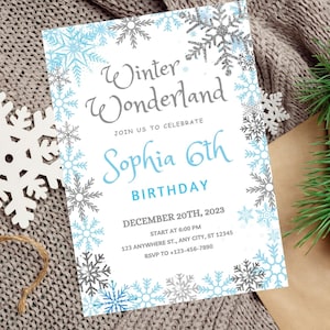 Può includere: Un invito bianco con un bordo di fiocchi di neve blu e grigi. Il testo recita "Winter Wonderland" con un "Sophia 6th Birthday" blu sotto. L'invito include la data, l'ora e la posizione dell'evento.