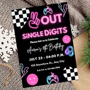 May include: A black and pink birthday invitation with neon text that reads "OUT SINGLE DIGITS" and "Aaron's 10th Birthday". The invitation includes a chequered pattern, a smiley face, a video game controller, and headphones.