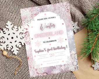 May include: A pink and white winter wonderland themed birthday invitation with snowflakes and a pink glitter font. The invitation says "Please join us for a winter wonderland to celebrate Sophia's first birthday!"
