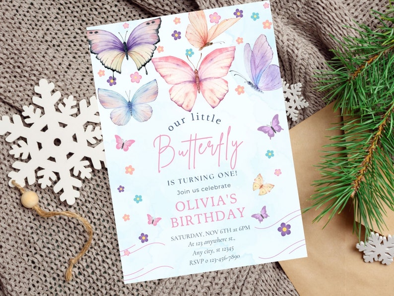 Puede incluir: Una invitaci&oacute;n azul y blanca con un dise&ntilde;o de mariposa de acuarela. El texto dice "nuestro peque&ntilde;o Butterfly est&aacute; cumpliendo un a&ntilde;o! &Uacute;nase a nosotros para celebrar el cumplea&ntilde;os de Olivia. S&aacute;bado, 6 de noviembre a las 6 PM. En 123 anywhere st., Any city, st 12345. RSVP 0 123-456-7890."
