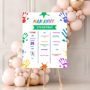 May include: A white birthday sign featuring colourful handprints and the text "MARIANNE 5TH BIRTHDAY". The sign includes information about the child's height, weight, favourite food, song, and other details.