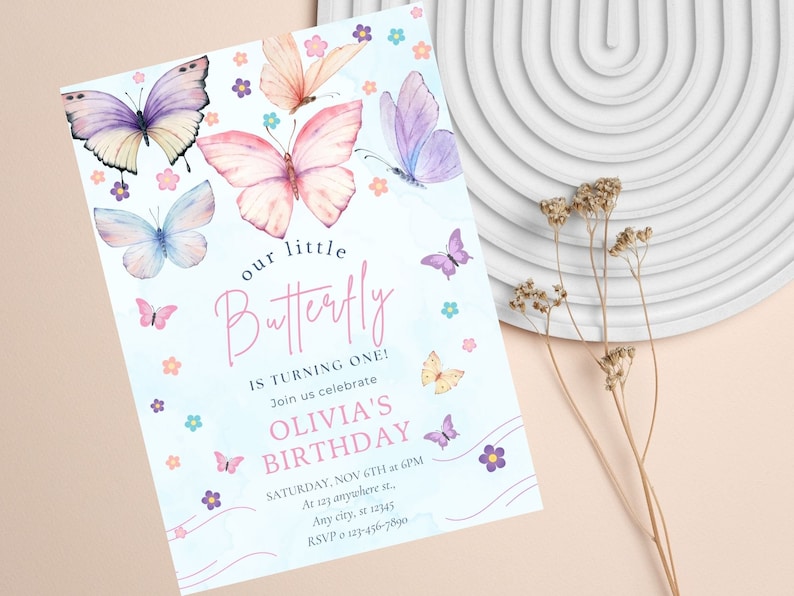 Puede incluir: Una invitaci&oacute;n azul y blanca con un dise&ntilde;o de mariposa de acuarela. El texto dice "nuestro peque&ntilde;o Butterfly est&aacute; cumpliendo un a&ntilde;o! &Uacute;nase a nosotros para celebrar el cumplea&ntilde;os de Olivia. S&aacute;bado, 6 de noviembre a las 6 pm. En 123 anywhere st. Any city, st 12345. RSVP 123-456-7890"