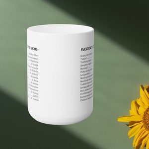 K&ouml;nnte beinhalten: Eine wei&szlig;e Keramiktasse mit schwarzem Text. Der Text auf der Tasse lautet "FOR MOMS" und listet eine Reihe von Namen auf, gefolgt von "EMERGENCY" und einer Liste von S&auml;tzen, die sich auf die Elternschaft beziehen.