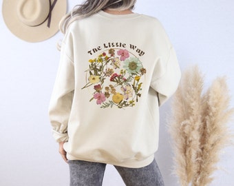 May include: A cream-colored sweatshirt with a floral design and the text "The Little Way" on the back.