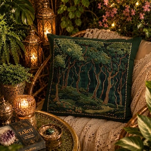 May include: A square throw pillow featuring an intricate embroidered forest scene with tall trees, textured foliage, and a dark green background. The design is framed by a border of small, light-colored beads along the edges of the fabric.