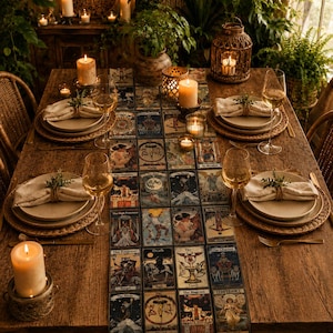 May include: A rectangular table runner featuring a grid of various tarot card illustrations in muted tones. The runner is centred on a wooden dining table set with beige plates, linen napkins, wine glasses, and several lit pillar candles.