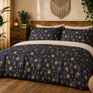 May include: A navy blue and gold celestial-themed duvet cover set with two matching pillowcases. The bedding features a pattern of gold sunbursts and circular designs. The reverse side of the duvet cover is a solid cream color. The set is displayed on a wooden bed frame.