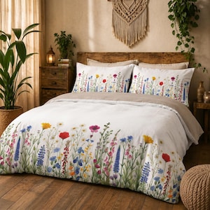 May include: A white duvet cover and two matching pillowcases featuring a colorful botanical print of wildflowers including red poppies, blue lupines, yellow daisies, and green stems. The bedding set is paired with a solid light brown top sheet.
