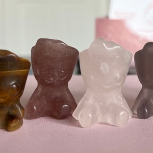 May include: Four small, hand-carved crystal figurines in the shape of bears. The bears are made of clear, rose quartz, tiger's eye, and smoky quartz.