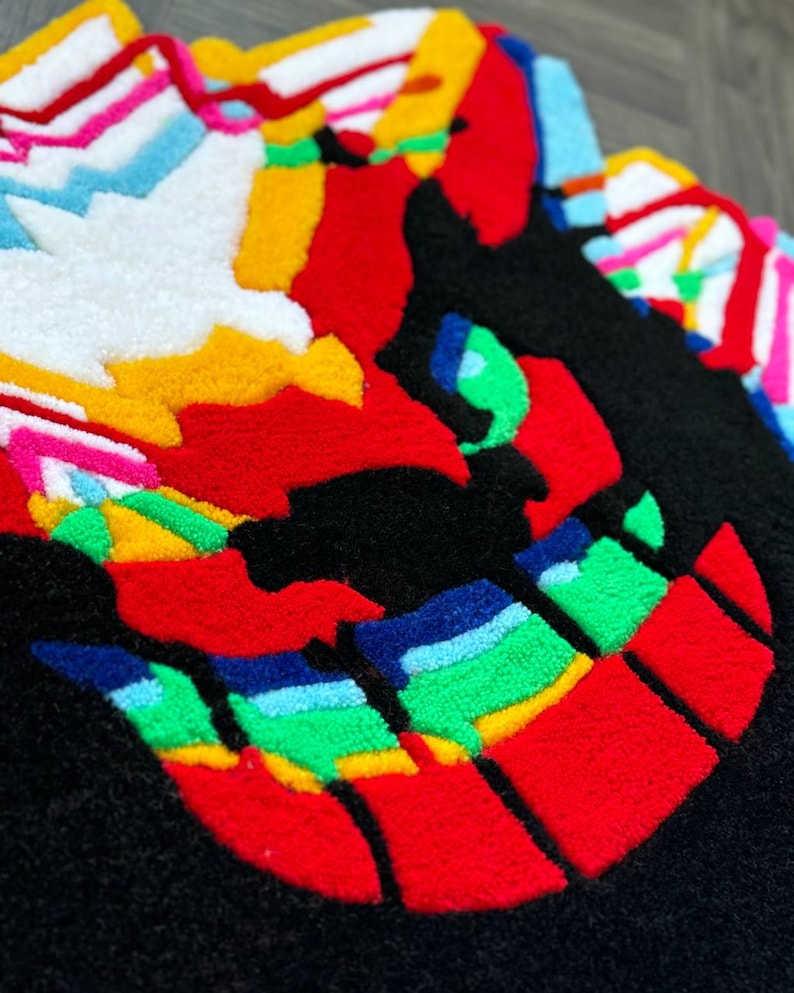 May include: A tufted rug featuring a stylized, multi-colored graphic design. The composition includes bold sections of black, vibrant red, bright yellow, white, light blue, and green yarn, creating a textured, high-contrast abstract pattern.