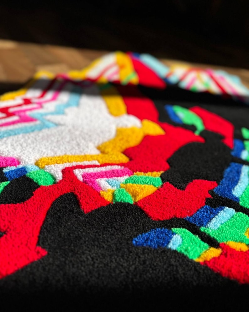 May include: A tufted textile piece featuring a high-contrast design with a black background and vibrant, raised yarn sections in red, white, yellow, bright pink, light blue, and green, creating a textured, multi-colored abstract pattern.