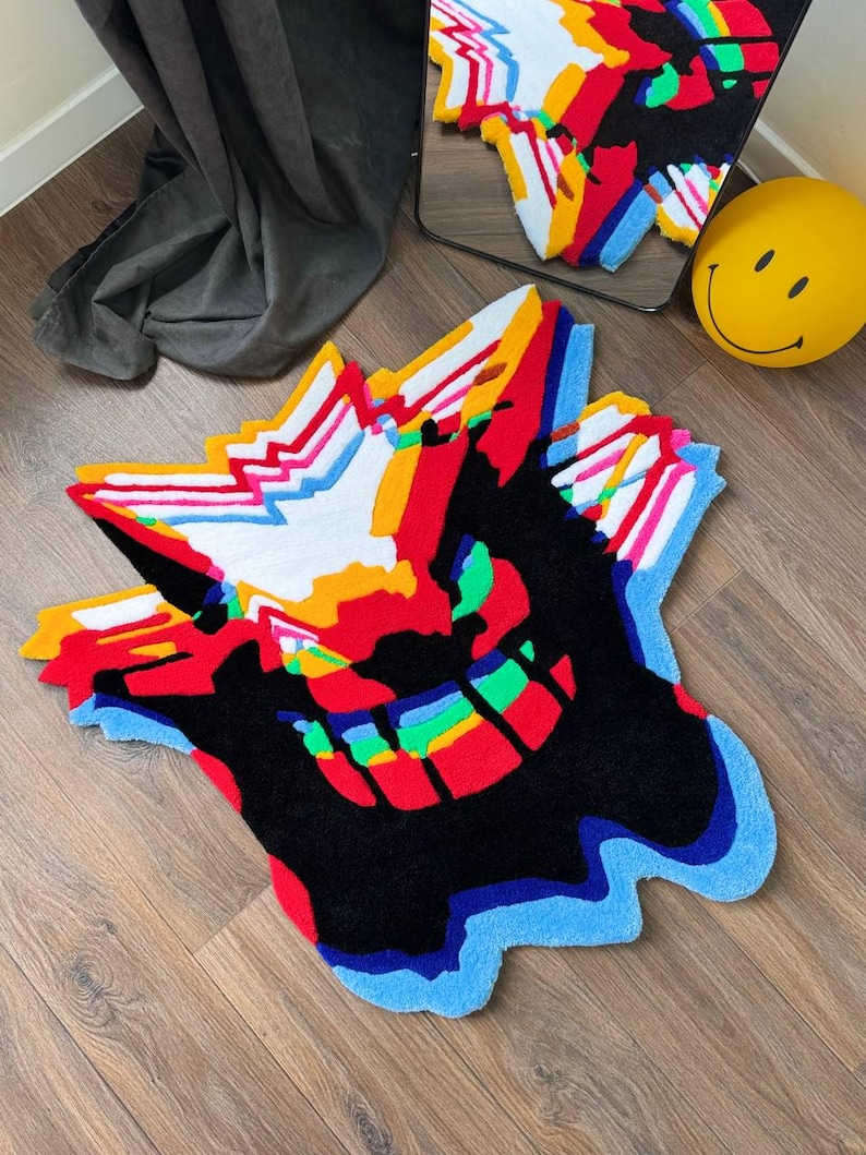 May include: A tufted rug featuring a stylized, abstract graphic design with a vibrant color palette of black, red, white, yellow, and blue. The rug has an irregular, jagged shape with layered, glitch-like patterns and a textured surface.