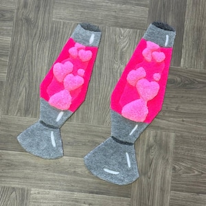 May include: Two gray and pink lava lamp shaped rugs with pink hearts in the center. The rugs are on a wood floor.