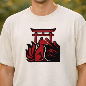May include: Cream-colored t-shirt featuring a red fox with nine tails, a Japanese torii gate, and mountains. The fox is sitting, facing right. The design is in a minimalist style.