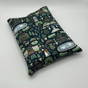 May include: A rectangular pillow with a dark teal background featuring a repeating pattern of garden scenes. The pattern includes birdcages, swans, trees, and figures. The pillow is filled and has a soft appearance.