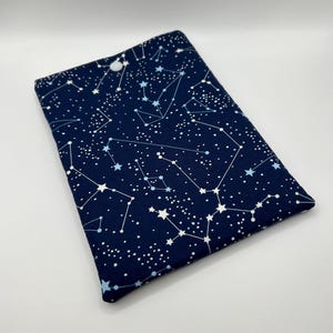 May include: A dark blue fabric pouch with a white button closure. The pouch is decorated with a white constellation pattern on a dark blue background.