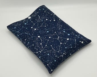 May include: A rectangular pillow with a dark blue background and a white and light blue constellation pattern. The pillow has a white button closure on one side. The fabric is patterned with stars and connecting lines.