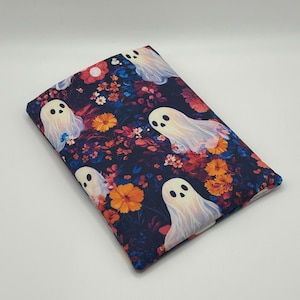 May include: A rectangular, fabric item featuring a repeating pattern of white ghosts with black eyes and mouths, set against a dark blue background filled with orange and red flowers and foliage. The item appears to be a case or cover.