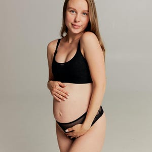 Pode incluir: Conjunto de sutiã e cueca de maternidade pretos. O sutiã tem alças ajustáveis e um design texturizado. A cueca apresenta uma borda de renda transparente. O conjunto foi projetado para conforto e suporte durante a gravidez.