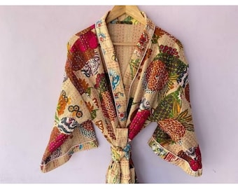 Puede incluir: Una bata de color crema con estampado floral en tonos rosa, verde, naranja y azul. La bata tiene un cinturón de atar y mangas largas.