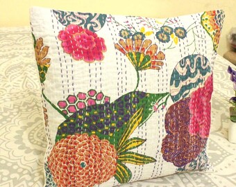 May include: Square white pillow with a colorful floral design. The pillow features a variety of flowers in shades of pink, orange, green, and purple. The design is stitched onto the pillow with white thread.