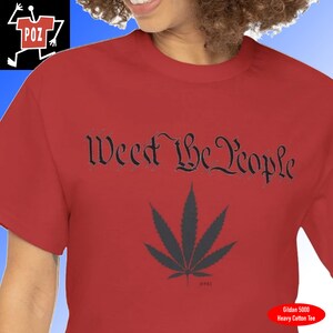 May include: Red t-shirt with the text "We the People" in a black, stylized font. A black marijuana leaf is below the text.