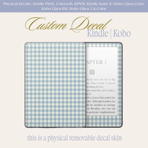 May include: A Kindle e-reader with a light blue and white gingham pattern decal. The open e-reader displays text from a book. The text "Custom Decal Kindle | Kobo" is at the top. The text "this is a physical removable decal skin" is at the bottom.