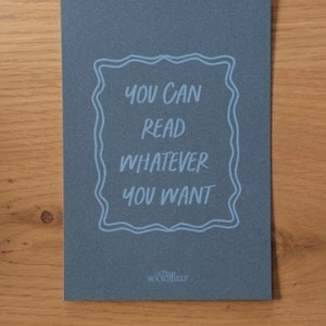 May include: A blue card with the text "You can read whatever you want" in a white frame. The text "The Bookshelf" is printed in white at the bottom of the card.