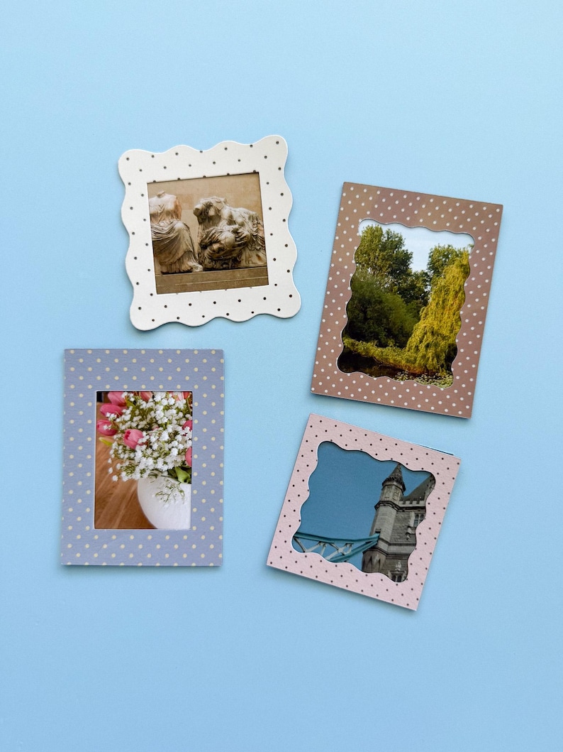 May include: Four decorative picture frames with scalloped edges and polka dots. The frames are in white, brown, light blue, and pink. The frames contain images of a sculpture, a landscape, a bouquet of flowers, and a building.