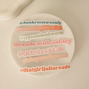 May include: A collection of colorful stickers with different book-related Instagram handles, including "@bookreviewsonly", "@romantasylibrarian", "@typeonebookworm", "@reads.with.ashley", "@debsbooktalk", "@alwaysreadingmore", and "@thatgirljuliareads".