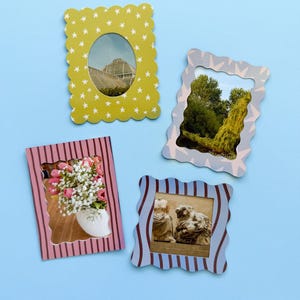 May include: Four decorative picture frames with scalloped edges and various designs. One frame is yellow with white stars, another is light blue with a wavy pattern, a third is pink with vertical stripes, and the last is blue with vertical stripes.