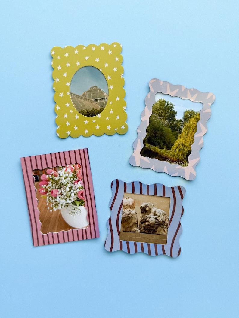 May include: Four decorative picture frames with scalloped edges and various designs. One frame is yellow with white stars, another is light blue with a wavy pattern, a third is pink with vertical stripes, and the last is blue with vertical stripes.
