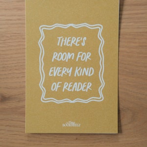 May include: A yellow card with white text that reads "There's room for every kind of reader" in a decorative frame. The text "Tiny Bookshelf" is at the bottom of the card.