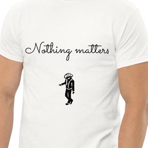 May include: White t-shirt with the text "Nothing matters" in black cursive font and a black silhouette of a person wearing a cowboy hat and a suit.