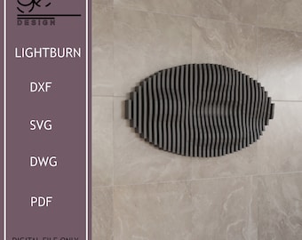 Puede incluir: Una decoración de pared ovalada de color negro y gris hecha de listones verticales delgados. Los listones están dispuestos en forma de onda. La decoración está montada en una pared de azulejos beige claro. El texto "LIGHTBURN" es visible en la imagen.