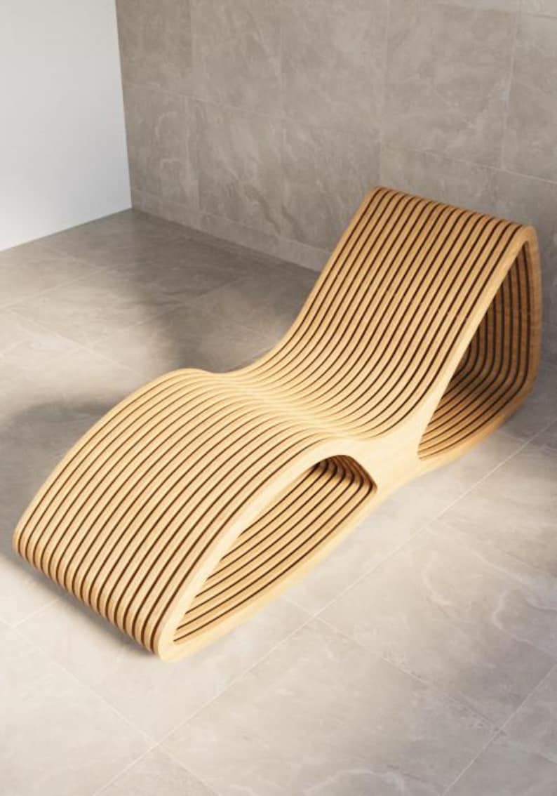 Puede incluir: Una moderna chaise longue de madera curvada. Est&aacute; construida con numerosas lamas de madera paralelas, creando una forma fluida y org&aacute;nica. La madera clara contrasta con el suelo y la pared de baldosas grises, creando una est&eacute;tica minimalista. Un mueble.