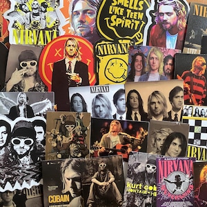 May include: A collection of various Nirvana-themed stickers and prints featuring Kurt Cobain and the band. The imagery includes band portraits, the iconic smiley face logo, concert photography, and text such as Smells Like Teen Spirit and Nevermind.