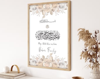 May include: A white framed print with a floral design and Arabic calligraphy. The text reads "May Allah bless our home" and "Babar Family".