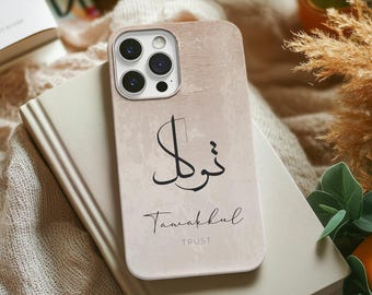 May include: A beige phone case with a wood grain texture. The case has a black Arabic word and the word "Tawakkul" written in English below it. The word "TRUST" is written in smaller letters below "Tawakkul".