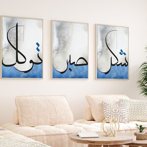 K&ouml;nnte beinhalten: Drei gerahmte Drucke mit arabischer Kalligraphie in Schwarz auf einem blauen und wei&szlig;en Aquarellhintergrund. Der Text lautet "Nishma", "Habib" und "Nukhl".