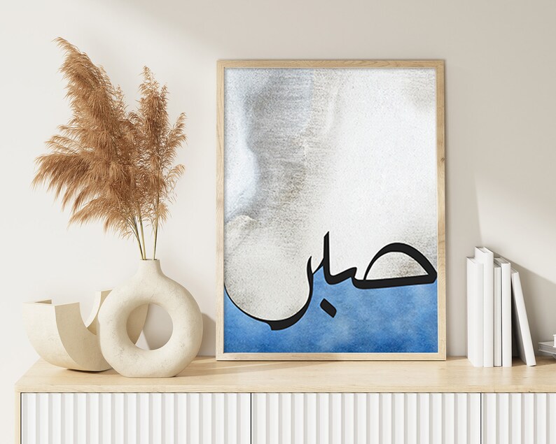 K&ouml;nnte beinhalten: Ein gerahmter Druck mit einem blauen und wei&szlig;en Aquarellhintergrund und schwarzer arabischer Kalligraphie, die "حب" lautet, was im Deutschen "Liebe" bedeutet.