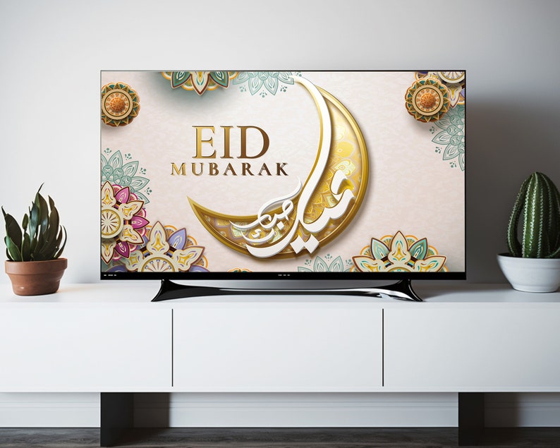 K&ouml;nnte beinhalten: Ein Fernsehbildschirm zeigt einen festlichen Eid Mubarak-Gru&szlig; mit einem goldenen Halbmond und komplizierten floralen Designs in Gr&uuml;n-, Blau- und Rosat&ouml;nen.