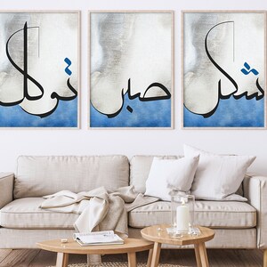 K&ouml;nnte beinhalten: Drei gerahmte Drucke mit arabischer Kalligraphie in Schwarz auf einem blauen und wei&szlig;en Aquarellhintergrund. Der Text lautet "Insha'Allah", "Bismillah" und "Alhamdulillah".