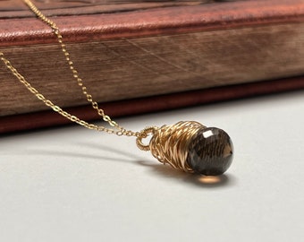 May include: A gold chain necklace with a brown gemstone pendant wrapped in gold wire.
