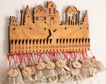 Op de afbeelding: Houten adventskalender met een silhouet van een stad. Het bruine houten frame heeft 24 genummerde sleuven, elk met een kleine beige stoffen zak met een houten label. Rode draad zet de zakken vast. Een feestelijke vakantiedecoratie.